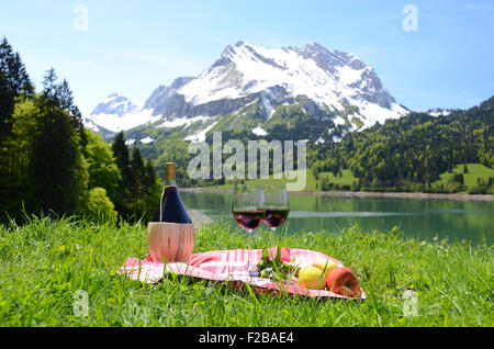 Il vino e le verdure servita presso un pic-nic nel prato alpino. Svizzera Foto Stock