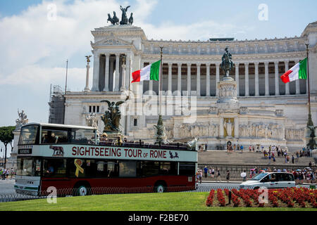 Un double decker bus tour passando il Monumento Nazionale a Vittorio Emanuele II in Roma, Italia. Foto Stock