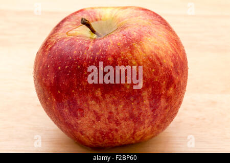 Red apple con gocce di acqua su un sfondo di legno Foto Stock