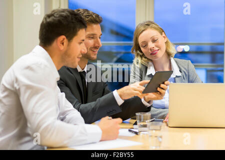 Uomini e donne d'affari sostenendo attraverso boardroom tavola utilizzando la tavoletta digitale Foto Stock