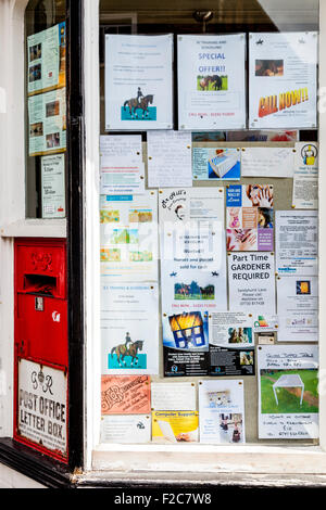 Una bacheca nella finestra del villaggio Post Office, High Street, Charing, Kent, Regno Unito Foto Stock