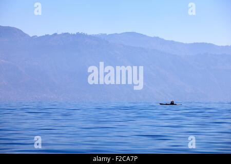 Blu profondo: lago Atitlan una piccola barca in silhouette contro Tuliman vulcano Foto Stock