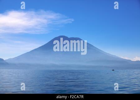 Blu profondo: lago Atitlan una piccola barca in silhouette contro Tuliman vulcano Foto Stock