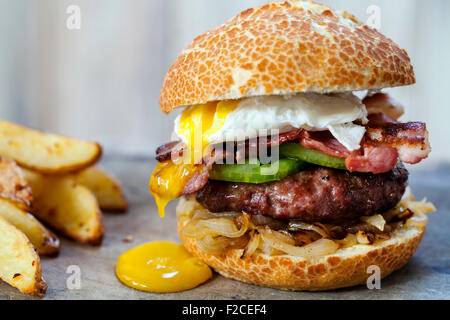 Hamburger di manzo con pancetta e uova in camicia Foto Stock