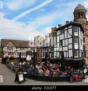 Persone nella affollata area con posti a sedere fuori il vecchio Wellington Inn e Sinclairs Oyster Bar nel centro della città, Manchester, Regno Unito. Foto Stock