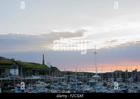 Barche nel porto di Whitehaven guardando verso la candela stick al tramonto Foto Stock