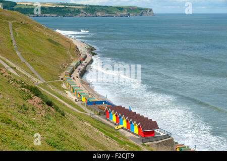 Multi-colore di cabine sulla spiaggia, a Whitby Beach, Whitby, nello Yorkshire, Inghilterra, Regno Unito. Sandsend Ness in distanza. Foto Stock