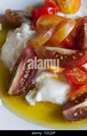 Guardando verso il basso in corrispondenza di burrata con pomodorini, corona di olio di oliva e sale di mare insalata Foto Stock