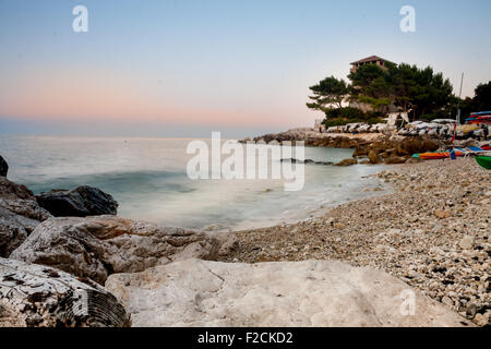 Torre e alberi di pino sulla spiaggia al tramonto Foto Stock