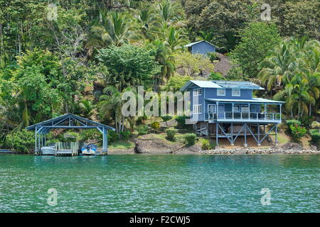 Proprietà costiere sul lussureggiante tropicale shore con imbarcazioni al dock e una casa sul mare dei Caraibi, Panama America Centrale Foto Stock