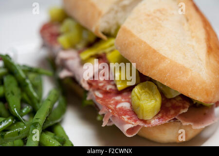 Stretto, close-up di calzone di prosciutto cotto, gypsy i peperoni e cipolla rossa con verde insalata di fagioli sul lato sulla piastra bianca Foto Stock