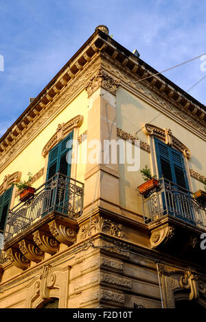 Un basso angolo di vista di intricati balconi in ferro battuto su un angolo di strada nel barocco strada principale di Noto, Sicilia, Italia Foto Stock