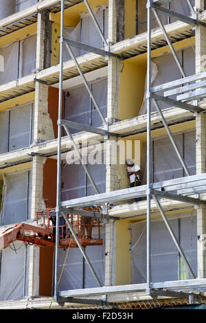 Lavoratore che indossa la sicurezza permanente di marcia su ponteggi guardando al suo smart phone Foto Stock