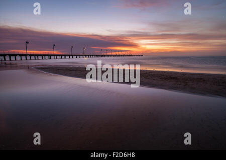 Acqua liscia superficie e pier in arancione tramonto Colori. Foto Stock