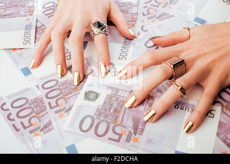 Le mani della donna ricca con golden manicure e molti gioielli anelli in contanti di Euro Foto Stock