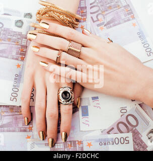 Le mani della donna ricca con golden manicure e molti gioielli anelli in contanti di Euro Foto Stock