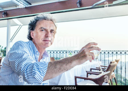 Momenti magici da condividere come una tranquilla cena presso il ristorante che si affaccia sul mare al tramonto: Nizza uomo di mezza età con la pelle morbida è di andare a bere Foto Stock