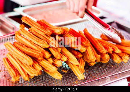 Pila di churros fritti dessert messicano e pinze Foto Stock