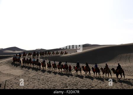 Jiuquan, la Cina della provincia di Gansu. Xvi Sep, 2015. I turisti corsa cammelli a scenic area di crescent molla del Mingsha Hill a Dunhuang, a nord-ovest della Cina di Provincia di Gansu, Sett. 16, 2015. © Zhang Xiaoliang/Xinhua/Alamy Live News Foto Stock