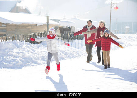 La famiglia felice in esecuzione nella neve Foto Stock