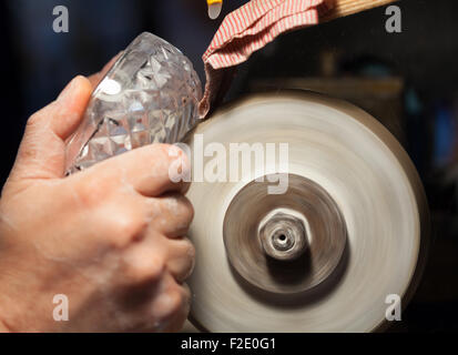 In prossimità delle mani di un artigiano durante la levigazione di un portacenere di cristallo Foto Stock