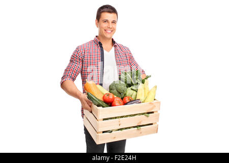 Giovane uomo allegro che porta una gabbia in legno pieno di verdure fresche isolati su sfondo bianco Foto Stock