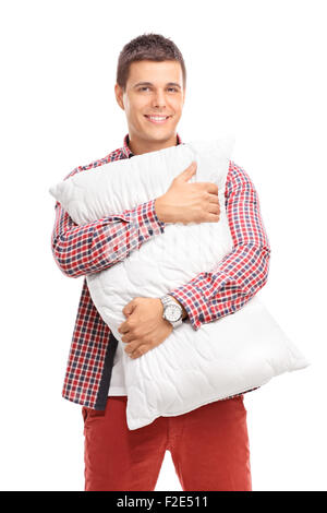 Colpo verticale del contenuto di un giovane uomo che abbraccia un cuscino bianco e guardando la telecamera isolata su sfondo bianco Foto Stock