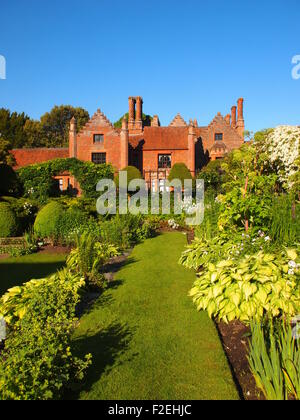 Chenies Manor, Buckinghamshire ai primi di giugno, lussureggiante verde in crescita il sunken garden nel tardo pomeriggio, cielo blu, visualizzazione verticale. Foto Stock