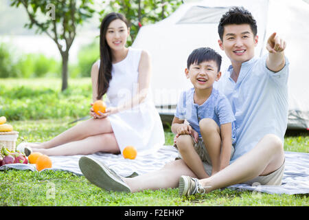 Felice famiglia giovane avente picnic sull'erba Foto Stock