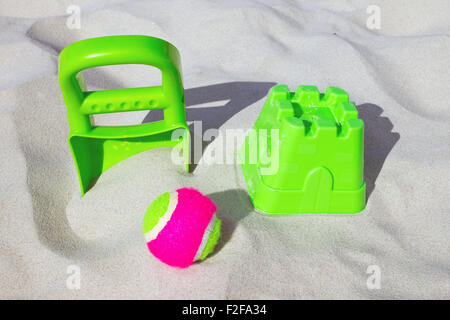 Giocattoli colorati e una sfera recante nella sabbia di una spiaggia Foto Stock