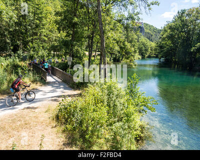 Percorso in bicicletta lungo il fiume Altmühl, gruppo di ciclisti in coda su un piccolo ponte, sul fiume Altmühl a destra, il castello di Prunn su Foto Stock