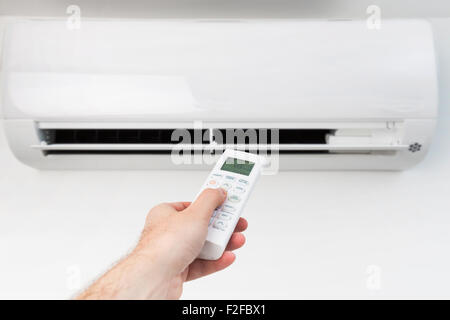 Mano con telecomando diretto sul condizionatore. Foto Stock