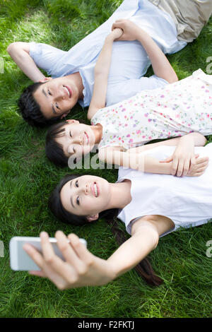 Felice famiglia giovane sdraiati sull'erba Foto Stock