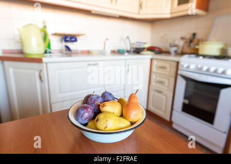 Tabella con una ciotola piena di pulire le pere e prugne in cucina Foto Stock