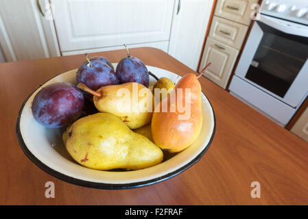 Tabella con una ciotola piena di pulire le pere e prugne in cucina Foto Stock