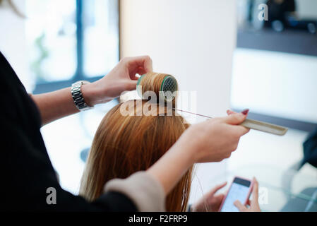 Parrucchiere incarto del cliente i capelli in bigodini in salone Foto Stock