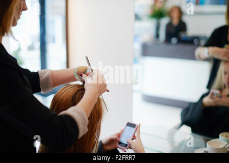 Parrucchiere di rotolamento del cliente i capelli in rulli in salone Foto Stock