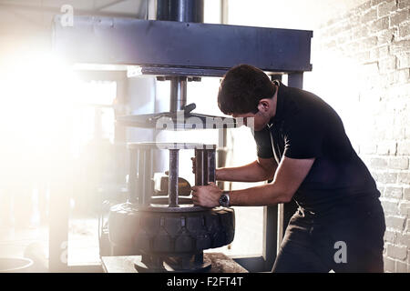 Mechanic utilizzando macchina smontagomme in negozio di riparazioni auto Foto Stock