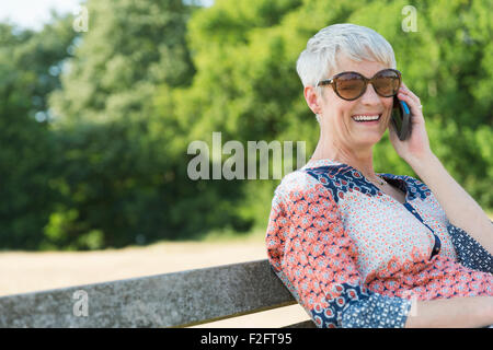 Sorridente donna senior parlando al cellulare in posizione di parcheggio Foto Stock