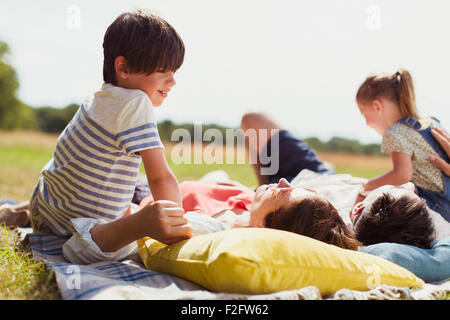 Famiglia relax su una coperta in campo soleggiato Foto Stock