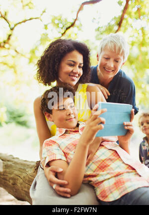 Multi-generazione famiglia utilizzando tavoletta digitale all'aperto Foto Stock