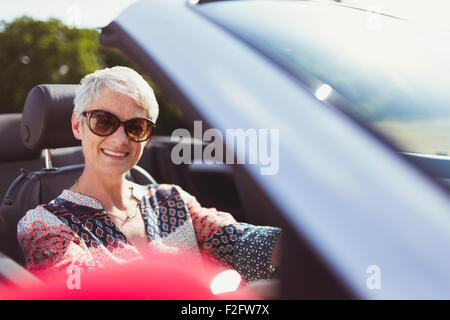 Ritratto sorridente donna senior in occhiali da sole convertibile di guida Foto Stock