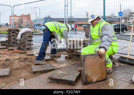 I lavoratori di posa della pavimentazione tattile piastrelle standard e pietre per pavimentazione. Nottingham, Inghilterra, Regno Unito Foto Stock