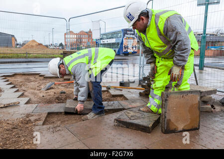 Lavoratori la posa di pavimentazioni tattili piastrelle standard e lastre per pavimentazione. Nottingham, Inghilterra, Regno Unito Foto Stock