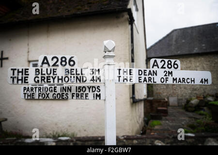 Insolito cartello stradale sulla A286 che mostra le distanze di case pubbliche pub Singleton Sussex Foto Stock