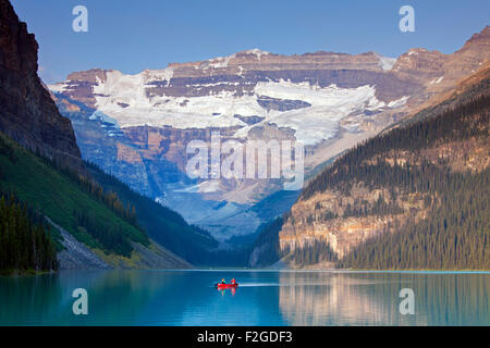 I turisti in rosso in canoa sul lago glaciale di Louise con Ghiacciaio Victoria, il Parco Nazionale di Banff, Alberta, Canada Foto Stock