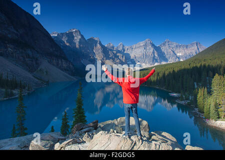 Turistico con le braccia aperte sul look-out point guardando sopra il Lago Moraine nella Valle dei Dieci Picchi, Banff NP Alberta, Canada Foto Stock