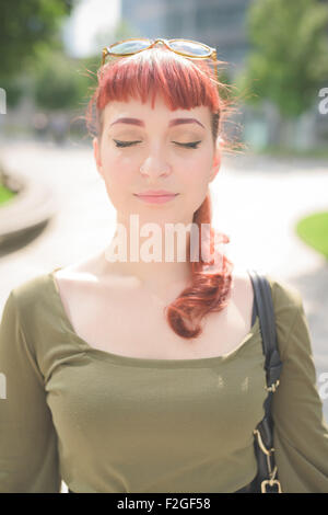 Ritratto di un giovane bello caucasian redhead donna con gli occhi chiusi e serena - serenità, carefreeness concetto - indossare camicia verde Foto Stock