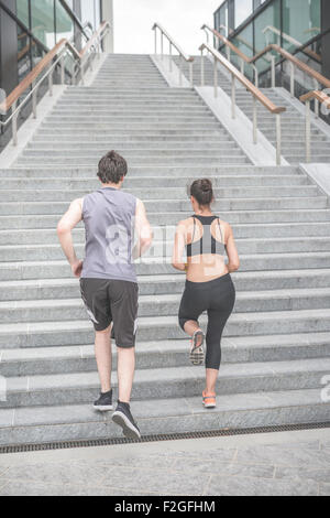 Coppia di giovani caucasici bello sportive l uomo e la donna in esecuzione al piano superiore, vista dal retro - attività sportive, sano concetto di fitness Foto Stock