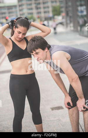 Coppia di giovani sportivi caucasica l uomo e la donna rilassante dopo la formazione, uno che guarda verso il basso e gli altri che si affaccia a destra Foto Stock